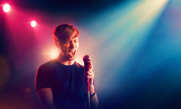 Young vocalist with a microphone singing on stage in backlit